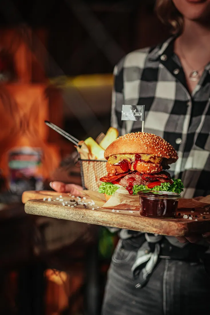 Kelnerka podaje burgera z frytkami na desce