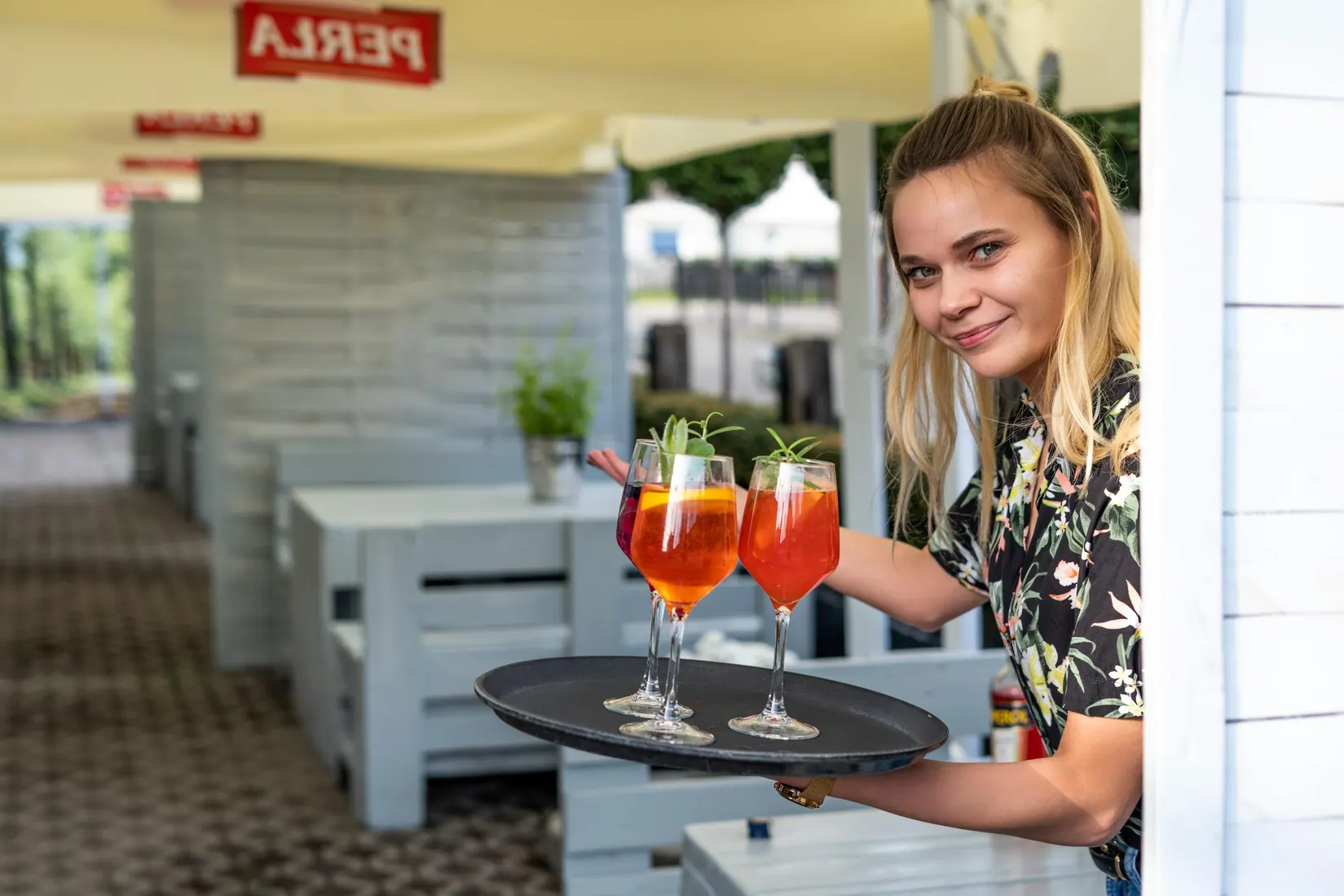 Kelnerka podaje koktajle w ogródku