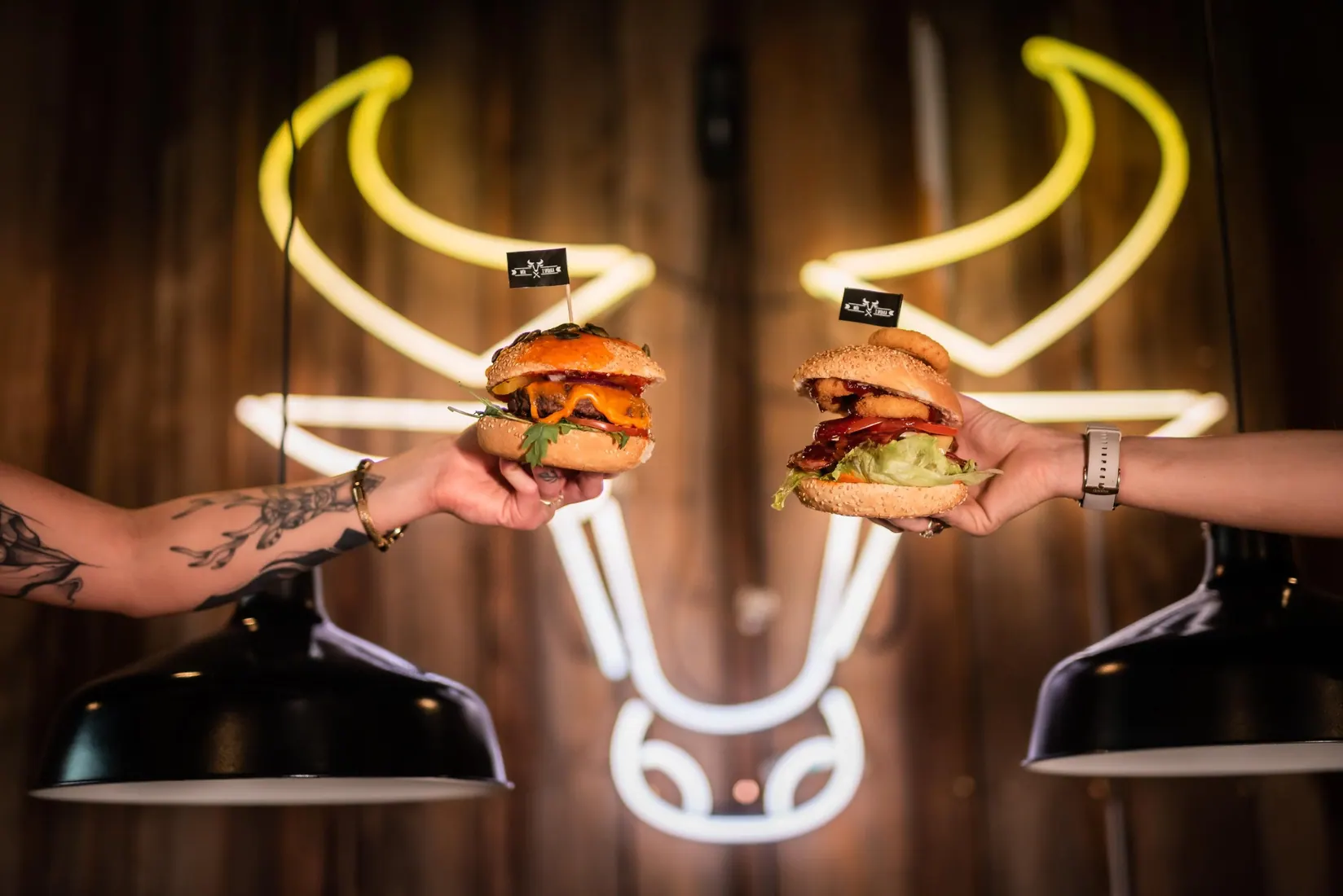 Dwa burgery na tle neonu byka w Wół i Spółka